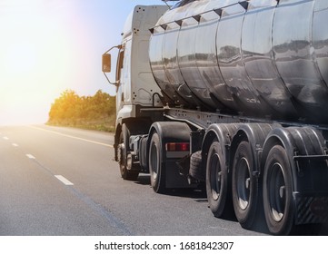 Fuel truck moving along a country road at sunrise.
