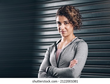 Fueled By Ambition. Portrait Of A Young Beautiful Woman Folding Her Arms Against A Black Background.