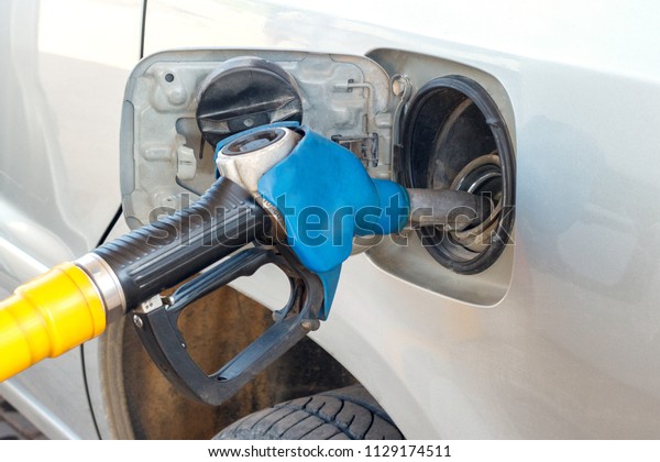 fueling car with gasoline, inserting gun into\
open fuel tank,\
close-up