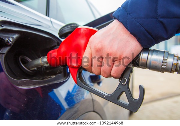 Fuelling gun\
inserted into the tank of blue\
car