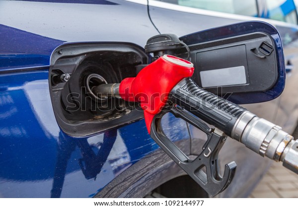 Fuelling gun\
inserted into the tank of blue\
car