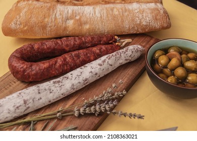 Fuets Catalan dry sausages. Set of spanish sausages and dry cured meat chistorra, chorizo, salchichon, fuet, olives, rosemary, chili peppers on a wooden background. top view. - Powered by Shutterstock