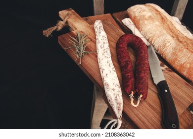 Fuets Catalan dry sausages. Set of spanish sausages and dry cured meat chistorra, chorizo, salchichon, fuet, olives, rosemary, chili peppers on a wooden background. top view. - Powered by Shutterstock