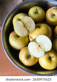 Fuji apples in water in a metal bowl and two apple halves, sliced ​​apple