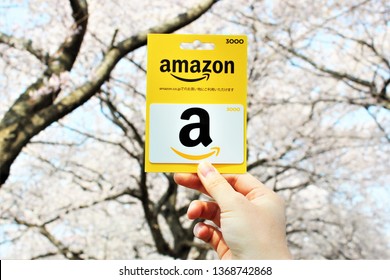 FUJIMINO, SAITAMA, JAPAN -April 7: My hand hold Amazon Gift Card of Japan with blur background of cherry blossom on April 7,2019 in FUJIMINO,SAITAMA,JAPAN.