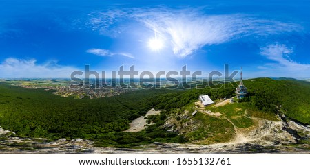Full 360 degree aerial drone panorama of Zobor telecommunication tower above the town of Nitra, Slovakia. Beautiful spherical photo of telecom tower in Slovak republic with blue sky, forest and city.