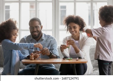 Full African family, loving daddy and mommy spend time with little children sculpting with plasticine using play dough having fun together on weekend, learning through play, pastime and hobby concept - Powered by Shutterstock