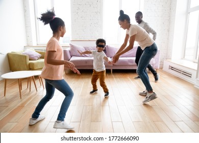 Full African Family Play Hide-and-seek Active Game Together With Blindfolded Toddler Son, Lively Mixed-race Siblings Running With Parents In Modern Light Living Room. Weekend Funny Activities Concept