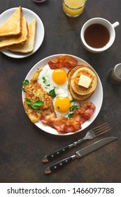 Full American Breakfast on dark, top view, copy space. Sunny side fried eggs, roasted bacon, hash brown, pancakes, toasts, orange juice and coffee for breakfast.