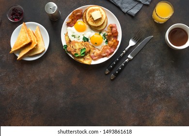 Full American Breakfast on white, top view, copy space. Sunny side fried eggs, roasted bacon, hash brown, pancakes, orange juice and coffee for breakfast.
