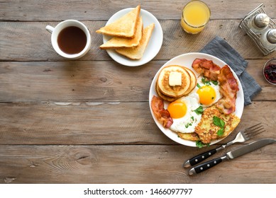 Full American Breakfast on wooden, top view, copy space. Sunny side fried eggs, roasted bacon, hash brown, pancakes, toasts, orange juice and coffee for breakfast. - Shutterstock ID 1466097797