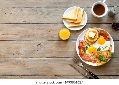 Full American Breakfast on wooden, top view, copy space. Sunny side fried eggs, roasted bacon, hash brown, pancakes, orange juice and coffee for breakfast. - Shutterstock ID 1493861627