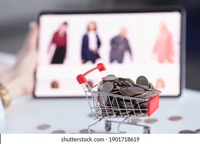 Full basket of coins on background of an online store with goods. Online shopping pros and cons concept