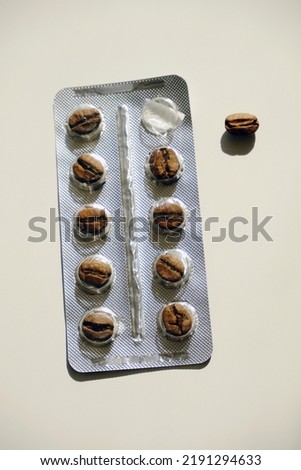 Full blister with coffee beans instead of tablets. One coffee pill taken out. Caffeine addiction concept