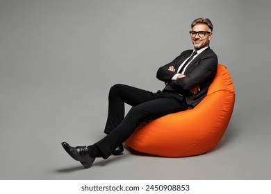 Full body adult employee business man corporate lawyer wear classic formal black suit shirt tie work in office sit in bag chair hold hands crossed folded look camera isolated on plain grey background - Powered by Shutterstock