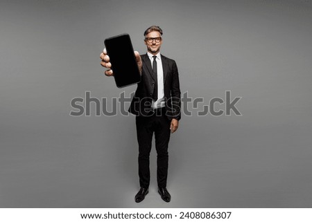 Full body adult employee business man corporate lawyer wear classic formal black suit shirt tie work in office hold use close up blank screen mobile cell phone isolated on plain grey background studio