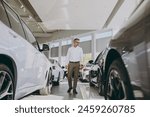 Full body adult man customer male buyer client he wearing classic shirt choose auto want to buy new automobile in modern car showroom vehicle salon dealership store motor show indoors. Sales concept