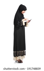 Full Body Of An Arab Saudi Woman Browsing A Smart Phone Isolated On A White Background               