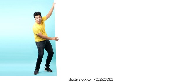 Full Body Asian Man Happy Smiling Shock And Surprise Face For Pulling Big White Board, On Blue Background In Studio With Copy Space For Ads.