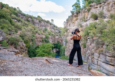 Full Body Back View Of Anonymous Barefoot Female Photographer Taking Photo Of Nature On Photo Camera While Standing On Edge Of Rocky Cliff