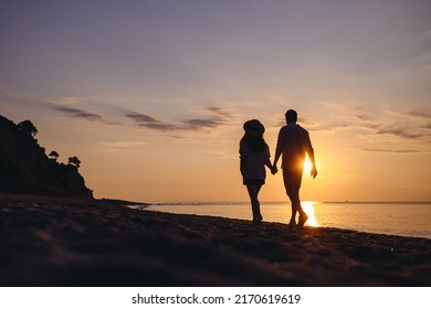 Full Body Back View Silhouette Young Couple Two Friends Family Man Woman In Casual Clothes Hold Hands Walk Stroll Together At Sunrise Over Sea Beach Ocean Outdoor Exotic Seaside In Summer Day Evening