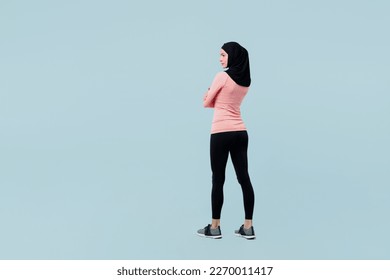 Full body back view young asian muslim fitness trainer sporty woman wear pink abaya hijab spend time in gym hold hands crossed isolated on plain blue background studio. Workout sport fit abs concept - Powered by Shutterstock