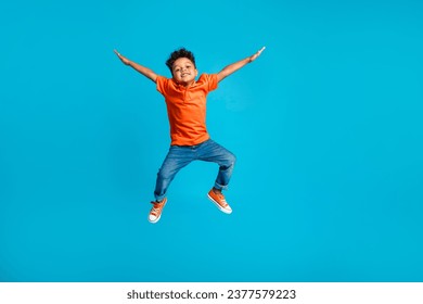 Full body cadre of jumping energetic latin small kindergarten age boy hands up positive star symbol hands isolated on blue color background - Powered by Shutterstock