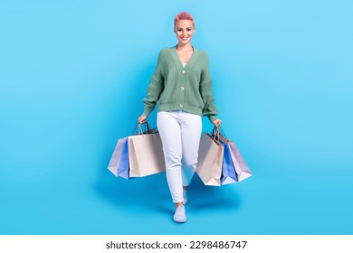 Full body cadre of satisfied stylish wear model promoter beautiful woman with bags from new yorker store isolated on blue color background