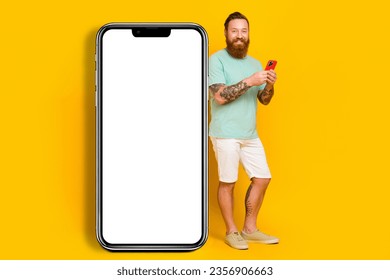 Full body cadre of youngster wear green t-shirt hold phone browsing interface new apple device ios device screen isolated on yellow color background