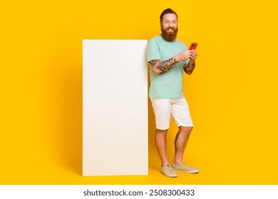 Full body cadre of youngster wear green t-shirt hold phone browsing interface new apple device ios device screen isolated on yellow color background