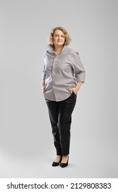 Full Body Casual Portrait Of Senior Woman In Grey Shirt And Trousers Over Grey Studio Background