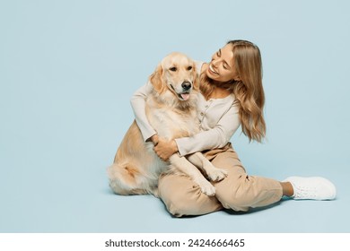 Full body cheerful lovely young owner woman wearing casual clothes sitting hug cuddle embrace her best friend retriever dog isolated on plain light blue background studio. Take care about pet concept - Powered by Shutterstock