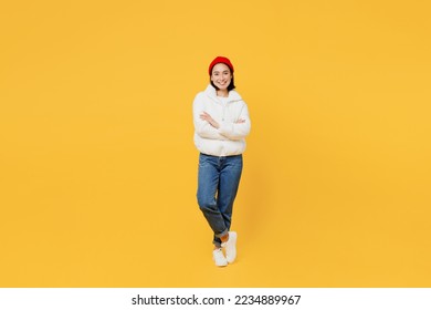 Full body cheerful young woman of Asian ethnicity wear white padded windbreaker jacket red hat hold hands crossed folded isolated on plain yellow background studio portrait. People lifestyle concept - Powered by Shutterstock