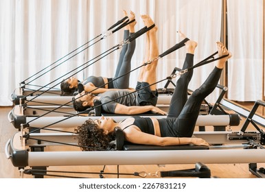 Full body of concentrated people in activewear doing exercises on pilates reformer during workout in gym - Powered by Shutterstock