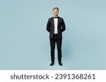 Full body confident smiling fun adult barista male waiter butler man wear shirt black suit bow tie uniform looking camera work at cafe isolated on plain blue background. Restaurant employee concept