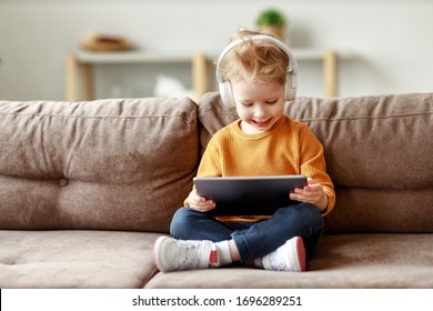 Full body delighted little boy in headphones smiling and watching interesting cartoon on tablet while sitting crossed legged on sofa at home
 - Powered by Shutterstock