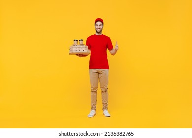 Full Body Delivery Guy Employee Man In Red Cap T-shirt Uniform Work As Dealer Courier Hold Pizza In Cardboard Flatbox Takeaway Craft Cup Coffee To Go Show Thumb Up Isolated On Plain Yellow Background.