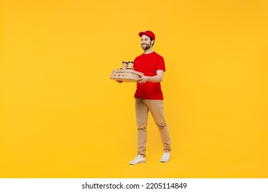 Full Body Delivery Guy Employee Man In Red Cap T-shirt Uniform Workwear Work As Dealer Courier Hold Pizza In Cardboard Flatbox Takeaway Craft Brown Cup Coffee To Go Isolated On Plain Yellow Background