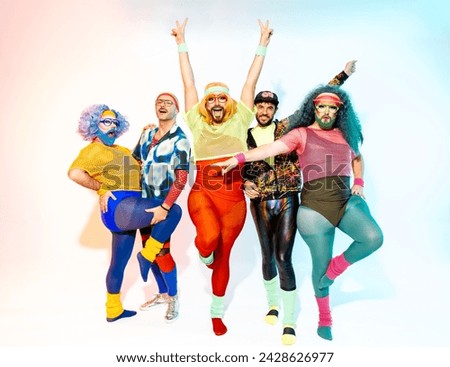 Full body of drag queens in colorful body fit sportswear and costumes standing together in various feminine style in studio with white background