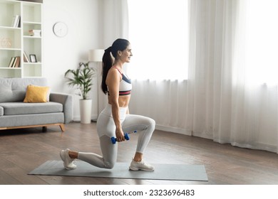 Full body dumbbell workout at home. Strong attractive slim well-fit young woman wearing white sportswear exercising with dumbbells, standing on fitness mat, copy space, living room interior - Powered by Shutterstock