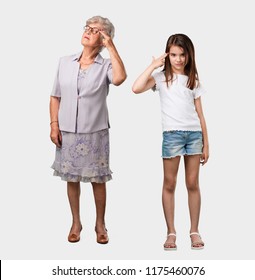 Full body of an elderly lady and her granddaughter making a suicide gesture, feeling sad and scared forming a gun with fingers