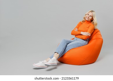 Full body elderly satisfied cheerful smiling happy blonde woman 50s in orange turtleneck sit in bag chair look camera isolated on plain grey color background studio portrait. People lifestyle concept - Powered by Shutterstock