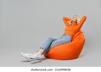 Full body elderly satisfied dreamful smiling happy blonde woman 50s in orange turtleneck sit in bag chair hold hands behind neck head take nap isolated on plain grey color background studio portrait - Powered by Shutterstock