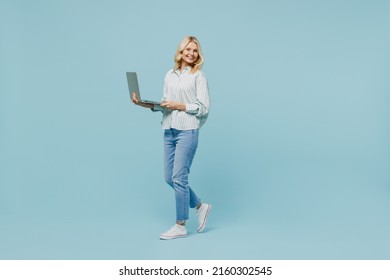 Full body elderly woman 50s wearing casual striped shirt hold use work on laptop pc computer surfing internet isolated on plain pastel light blue color background studio. People lifestyle concept. - Powered by Shutterstock