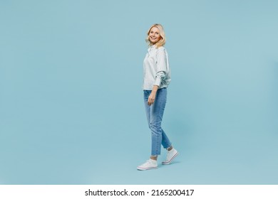 Full Body Elderly Woman 50s Wearing Casual Striped Shirt Looking Camera Walk Go Strolling Loook Camera Isolated On Plain Pastel Light Blue Color Background Studio Portrait. People Lifestyle Concept.