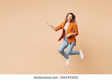 Full body expressive overjoyed cool singer young woman she wear orange shirt casual clothes jump high play air guitar isolated on plain pastel light beige background studio portrait. Lifestyle concept - Powered by Shutterstock