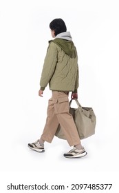 Full Body Fashion Model. Man In Warm Jacket With Khaki Pants Holding Handbag Walking In Studio On White Background