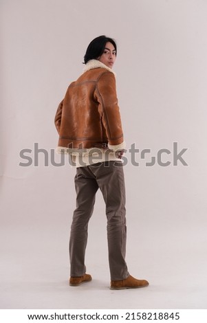 Full body fashion model. man in warm brow jacket with brown jeans posing in studio