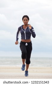 Full Body Front Portrait Of Healthy African American Woman Running At The Beach