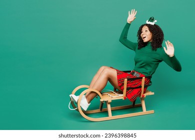 Full body fun merry little kid teen girl wear hat casual clothes posing sledding spread hands isolated on plain green background studio portrait. Happy New Year celebration Christmas holiday concept - Shutterstock ID 2396398845
